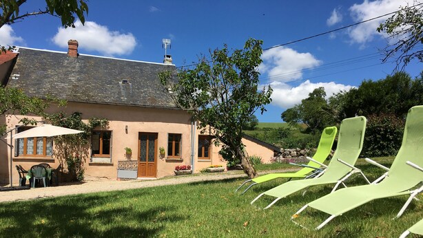 Une maison avec un jardin, du mobilier d’extérieur et un ciel dégagé.