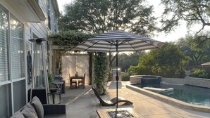 Un patio con mobiliario exterior, una fogata y una piscina.