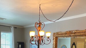 Un comedor con candelabro, un jarrón con flores y un espejo grande.