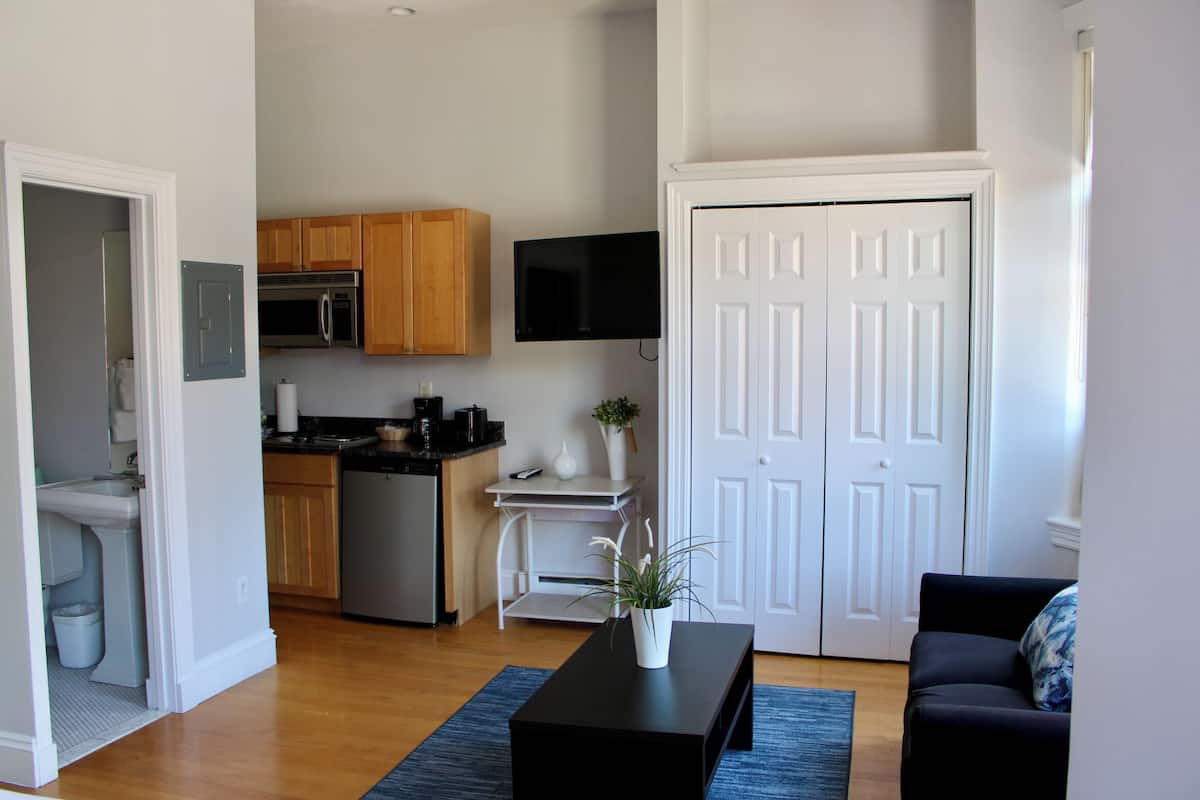 A modern kitchen with wooden cabinets, a built-in microwave, and a small dining area.