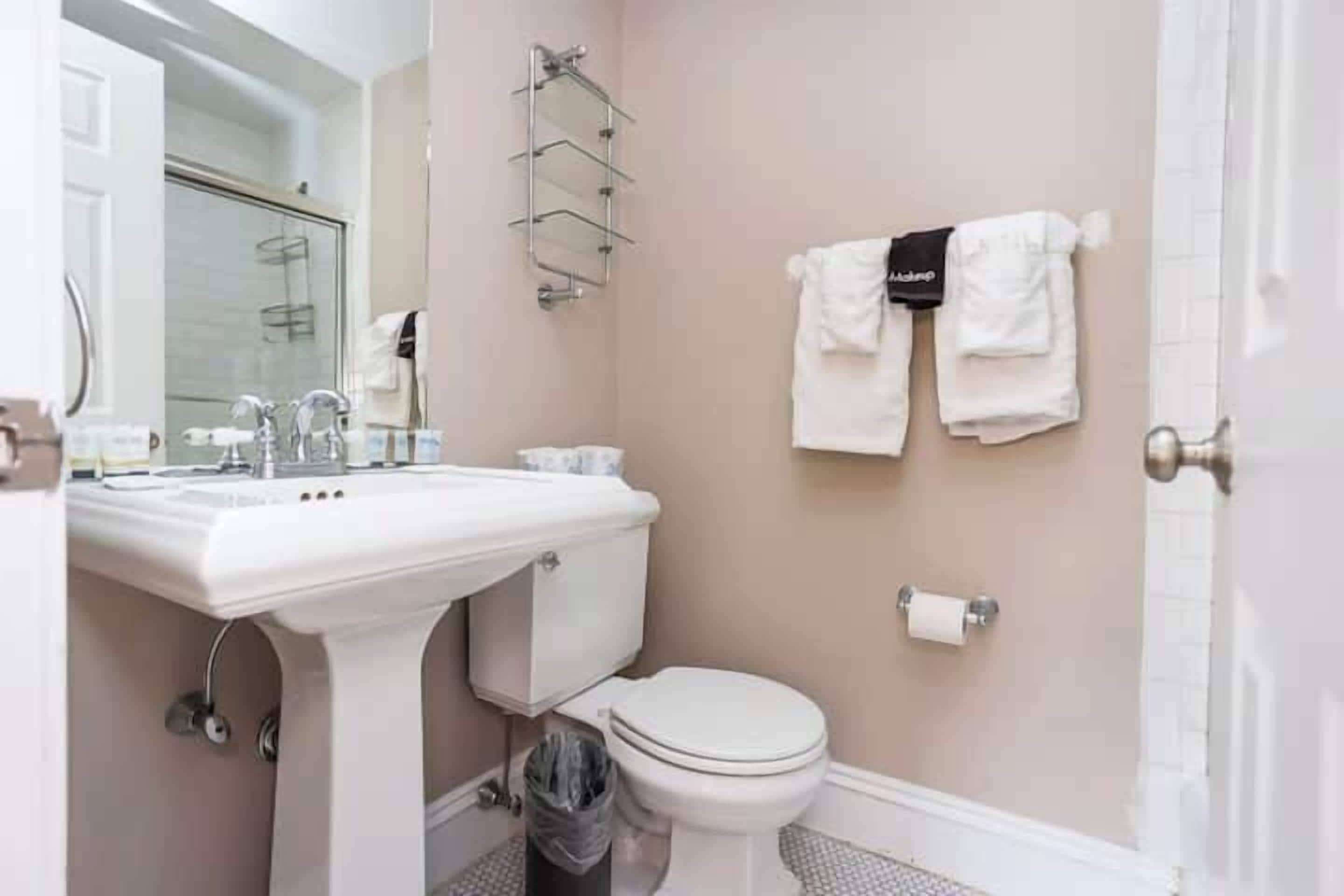 A bathroom with a white sink, toilet, and a towel rack with two towels.
