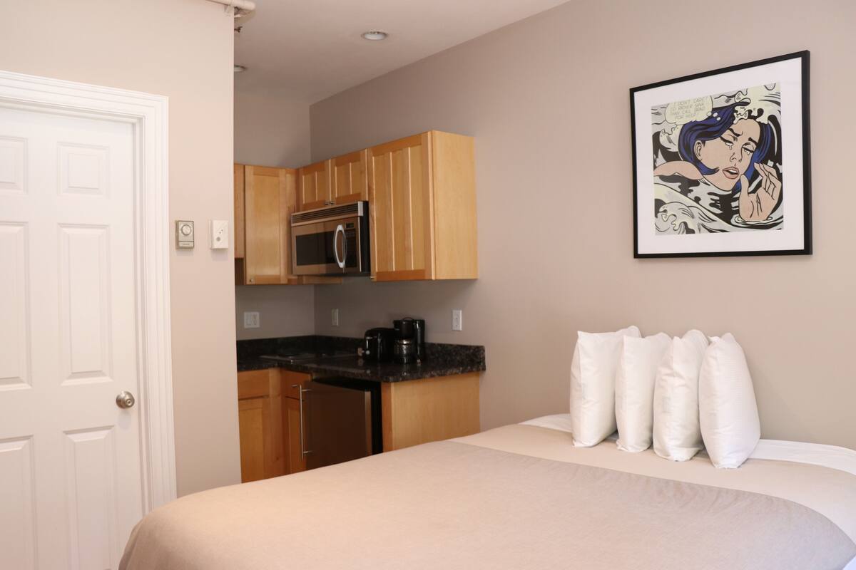 A bedroom with a bed, a nightstand, and a framed picture on the wall.