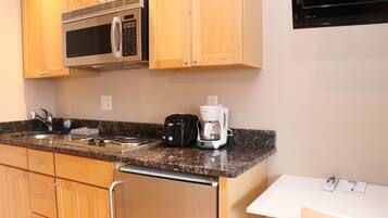 A kitchen with wooden cabinets, a stainless steel microwave, a toaster, and a coffee maker.