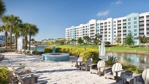 A resort with a pool, lounge chairs, and a water fountain. - Adventure Park Vacation 1 BR Condo with Tropical Pool (Orlando)