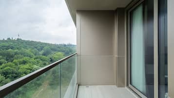 Uma varanda com guarda-corpo de vidro com vista para uma paisagem verde.