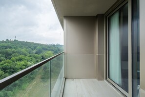A balcony with a glass railing overlooking a green landscape.