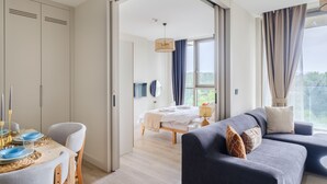 A modern hotel room with a dining area, a bed, a sofa, and a large window offering a view. - As Maslak by NewInn (Sariyer)