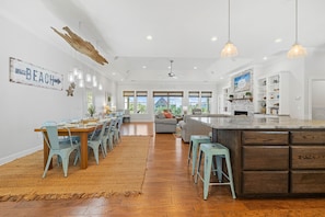 Une cuisine spacieuse avec un grand îlot central, une table à manger en bois et des chaises bleu clair.