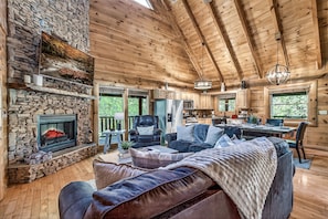 Un intérieur de chalet chaleureux avec une cheminée en pierre, un plafond en bois et un coin repas.