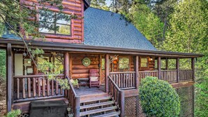 A log cabin with a porch, outdoor seating, and a covered area.