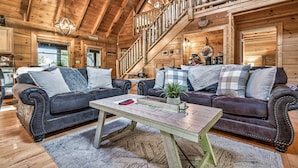 A wooden interior with two leather sofas, a wooden coffee table, and a staircase.