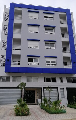Un bâtiment moderne doté de nombreux balcons, de grandes fenêtres et d’une entrée sécurisée par un portail.