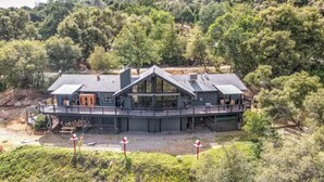 A large, modern house with a prominent balcony and a garage. - 🌙 Crescent Chalet - Hot Tub, Views, Sauna! (Oakhurst)