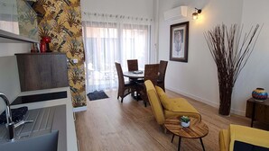 A modern living room with a dining area, wooden flooring, and a kitchen with a sink and cabinets. - Charming town center residence with terrace and view of the Canigou mountains (Thuir)