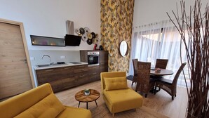 A modern living room with a sofa, a coffee table, and a dining area with chairs and a table. - Charming town center residence with terrace and view of the Canigou mountains (Thuir)