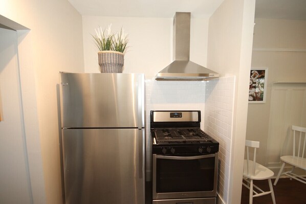 A compact kitchen with a stainless steel refrigerator, a gas stove, and a built-in oven.