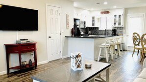 A modern kitchen with white cabinetry, a black countertop, and a dining area with white chairs and a wooden table. - Life is Better at the BEACH! Beautifully decorated and freshly updated retreat! (Panama City Beach)