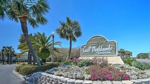 A sign for Gulf Dighlands Resort with a stone wall and flower beds. - Life is Better at the BEACH! Beautifully decorated and freshly updated retreat! (Panama City Beach)