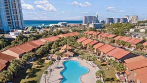A resort with a central swimming pool, multiple buildings with red roofs, and a view of the ocean. - Life is Better at the BEACH! Beautifully decorated and freshly updated retreat! (Panama City Beach)