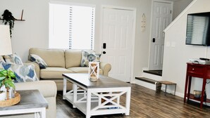 A living room with a sofa, coffee table, and a staircase leading to another level. - Life is Better at the BEACH! Beautifully decorated and freshly updated retreat! (Panama City Beach)