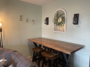 Un coin repas avec une table et des bancs en bois, un luminaire fixé au mur et des lettres décoratives formant le mot « EAT » sur le mur.