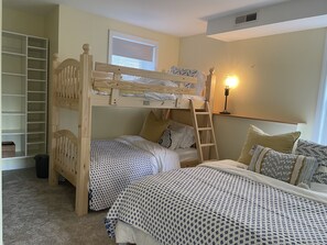 Une chambre avec un lit superposé, une échelle, une table de chevet et une lampe.