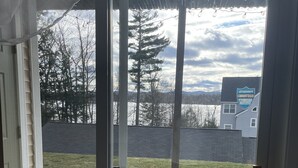 En vy från en skjutdörr i glas ut mot en gräsklädd trädgård, med ett hus i bakgrunden.