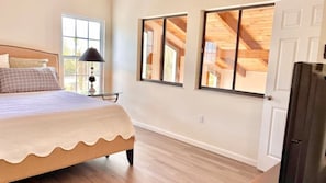 A bedroom with a bed, a nightstand, a lamp, and a window. - Treasure Coast Retreat (Fort Pierce)