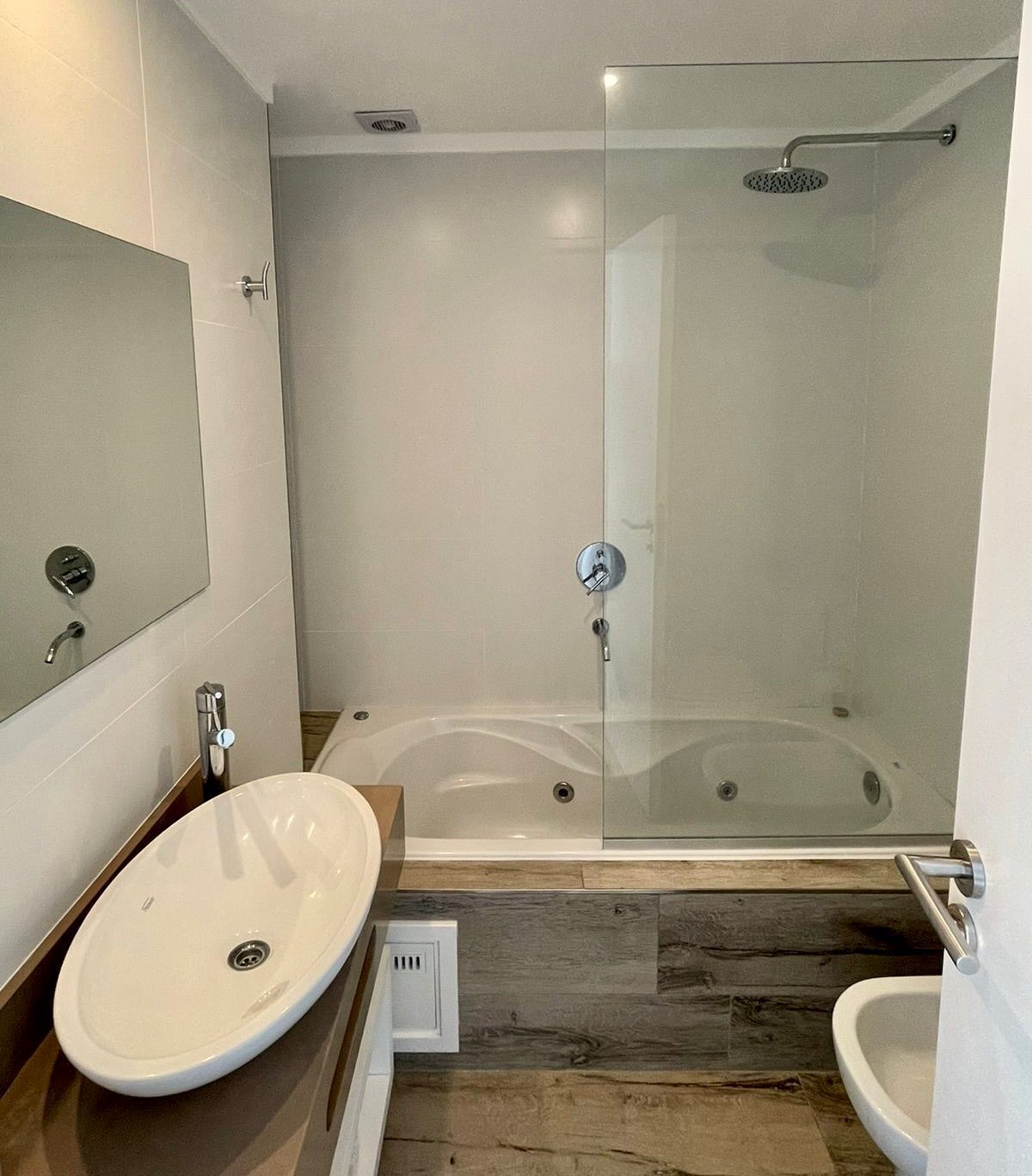 A modern bathroom with a glass-enclosed shower, a standalone sink, and a separate toilet.