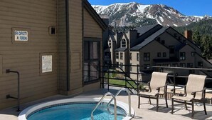 A pool area with a sign indicating a spa capacity of 8 persons, surrounded by buildings with a mountain backdrop.