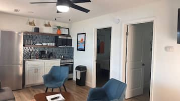 A compact kitchen with modern appliances, a dining area with two chairs, and a ceiling fan.
