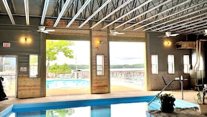 An indoor swimming pool with clear views of the surrounding area, including a lifeguard station and a view of the outdoors. - Alhonna Resort LLC (Lake Ozark)