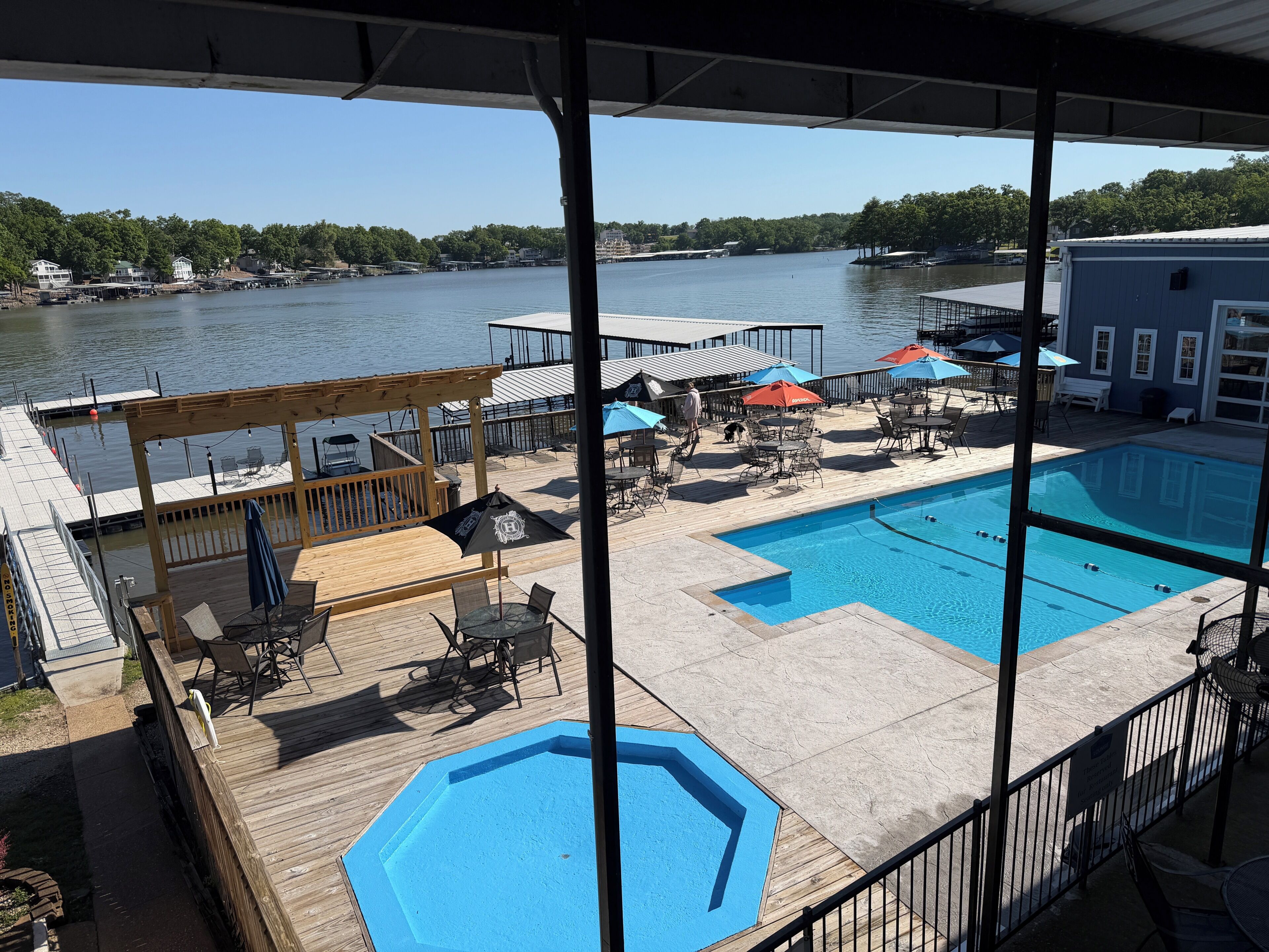 A pool area with two pools, outdoor seating, and a view of a river.