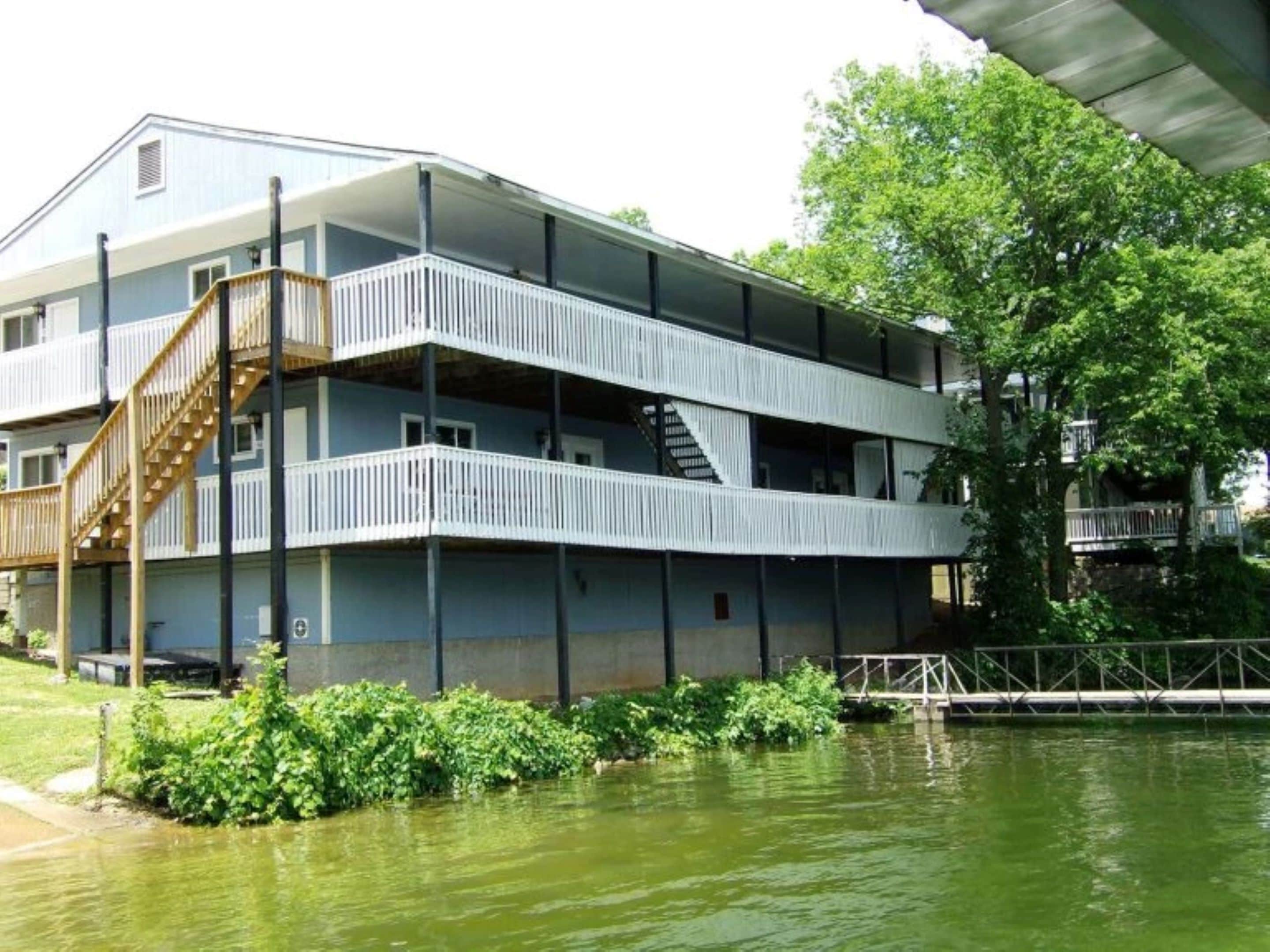 A multi-story building with balconies, a staircase, and a waterfront view.