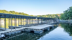 A dock extending into calm water with a clear sky and trees in the background. - Alhonna Resort LLC (Lake Ozark)