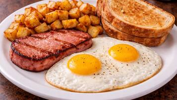 Un plato con bistec, huevos fritos, patatas ralladas y tostadas.