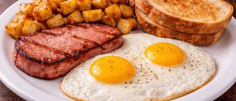 Un plato con bistec, huevos fritos, patatas ralladas y tostadas.