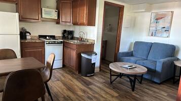 A compact living space with a kitchenette, a dining area, and a seating area with a couch and coffee table.