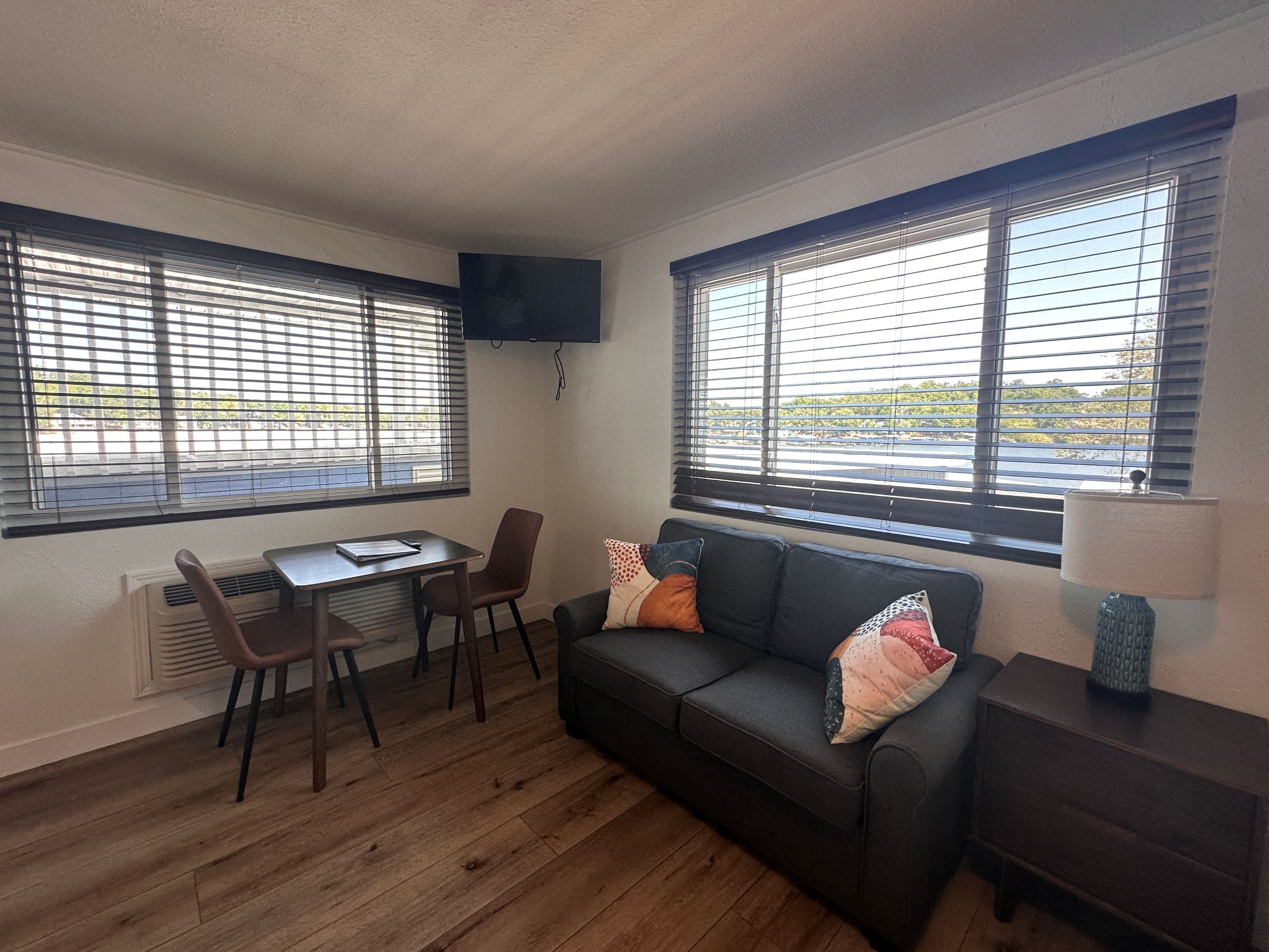 A compact living space with a sofa, two chairs, a small table, and a TV mounted on the wall.