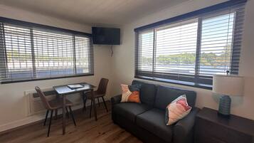 A compact living space with a sofa, two chairs, a small table, and a TV mounted on the wall.