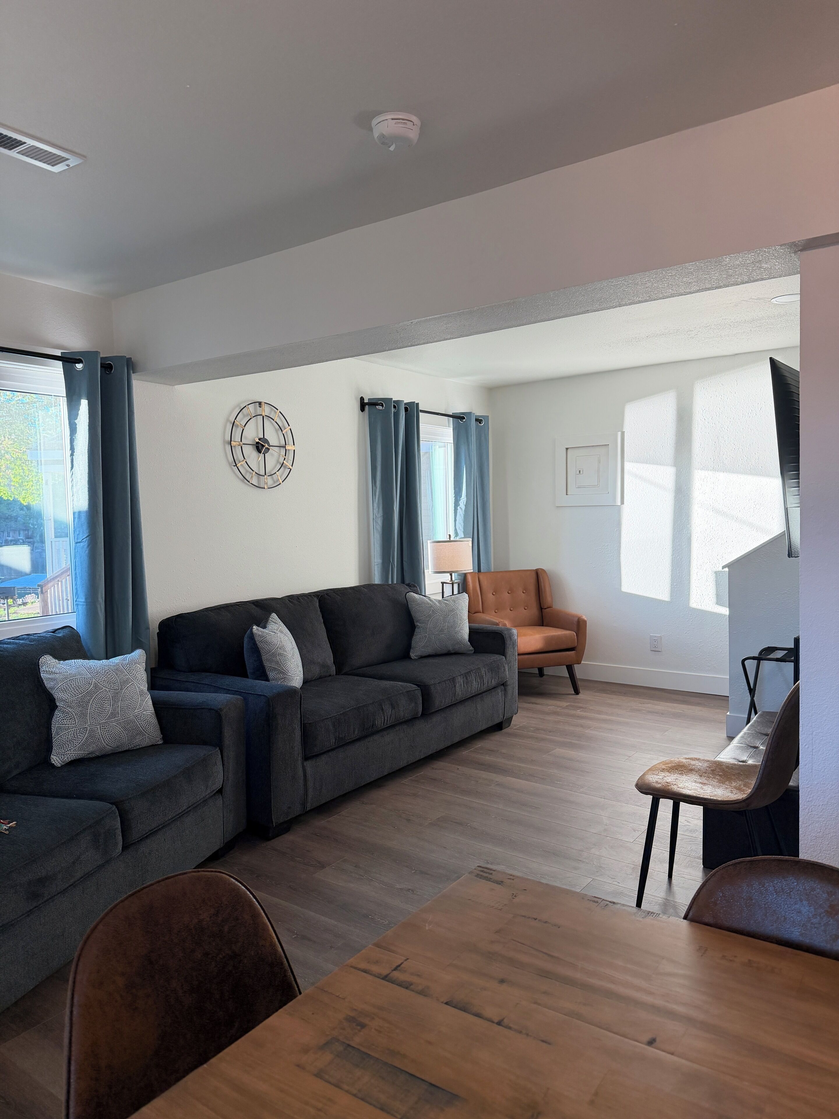 A modern living room with a sectional sofa, a dining table, and a chair.