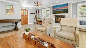 A living room with a piano, two armchairs, a wooden coffee table, and a fireplace. - Pine Summit | Hot Tub+Sauna | BBQ | Arcade + Games (Big Bear Lake)