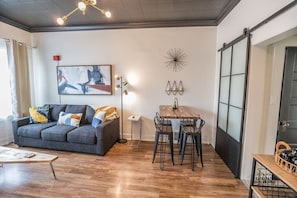 A modern living room with a sofa, a dining table, and chairs.