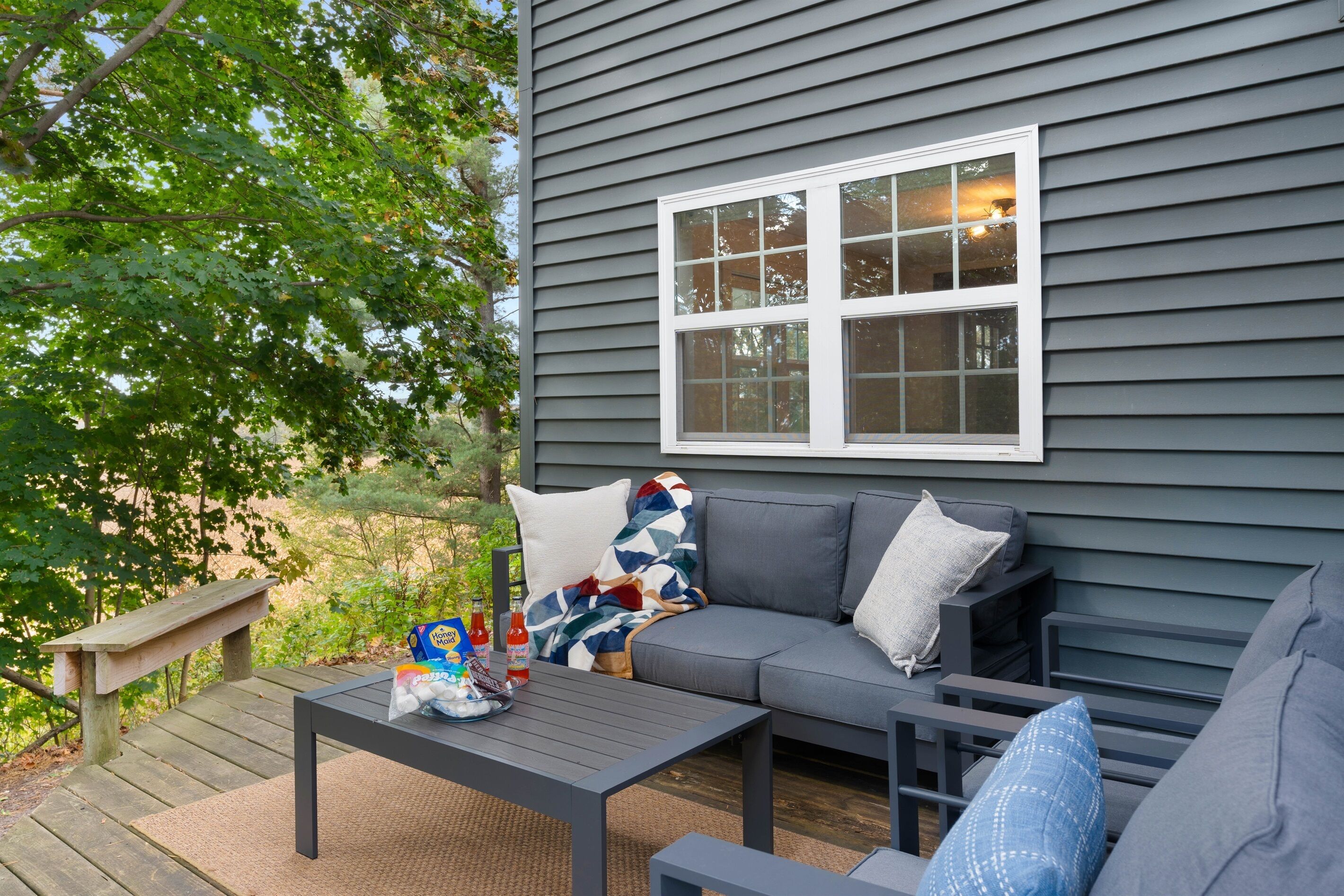 A patio with a gray sofa, a small table, and a bench.