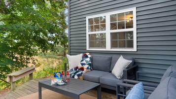 A patio with a gray sofa, a small table, and a bench.