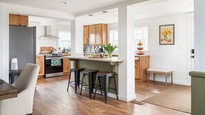 Una cocina moderna con armarios de madera, una isla central con taburetes y una zona de comedor con banco.