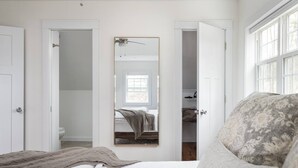 Un dormitorio con una cama, una mesita de noche, un espejo y una ventana.