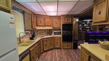 A kitchen with wooden cabinets, a built-in oven, a microwave, and a sink.