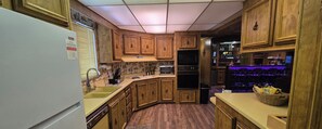 A kitchen with wooden cabinets, a built-in oven, a microwave, and a sink.