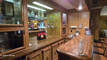 A wooden bar area with a coffee machine, hand sanitizer, and a clock on the wall.